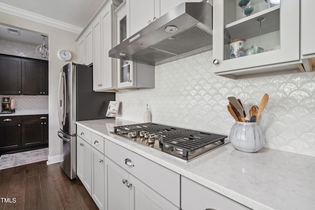 kitchen featuring exhaust hood, stainless steel gas cooktop, dark wood finished floors, crown molding, and decorative backsplash