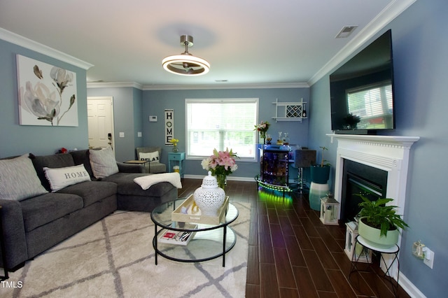 living area featuring baseboards, a glass covered fireplace, wood finished floors, and ornamental molding