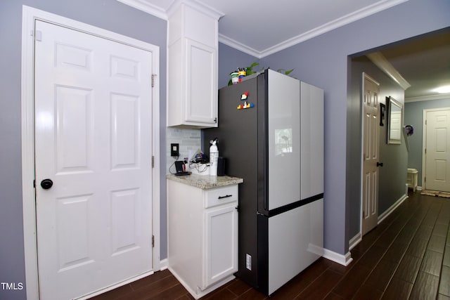 kitchen with freestanding refrigerator, crown molding, dark wood finished floors, baseboards, and white cabinets