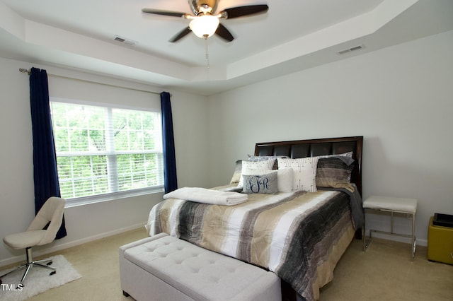 carpeted bedroom featuring a raised ceiling, baseboards, and ceiling fan