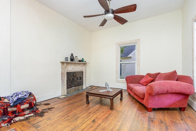living room with hardwood / wood-style flooring, ceiling fan, a fireplace, and baseboards