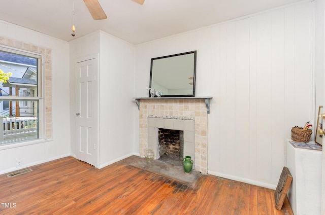 unfurnished living room featuring wood-type flooring, a ceiling fan, a fireplace, and baseboards