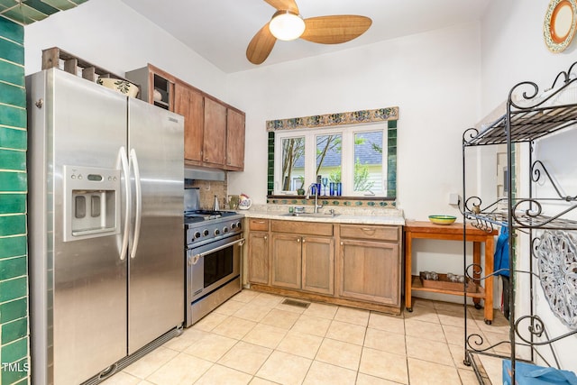 kitchen with appliances with stainless steel finishes, a sink, ceiling fan, light countertops, and brown cabinets