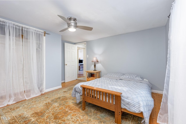 bedroom featuring wood finished floors, baseboards, and ceiling fan