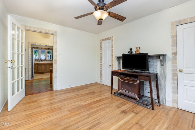 living area featuring wood finished floors, a ceiling fan, and crown molding