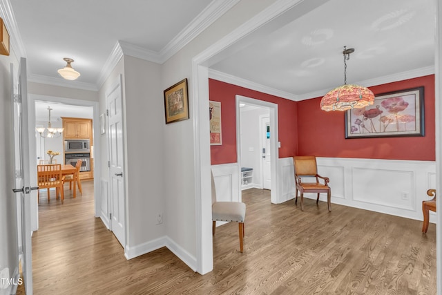 5805 Bayberry Ln, Raleigh, NC 27612 - entrance foyer with light wood-style flooring, a wainscoted wall, crown molding, and a chandelier
