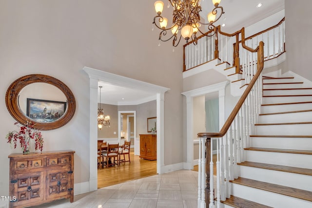 foyer featuring a chandelier, stairs, crown molding, baseboards, and a towering ceiling