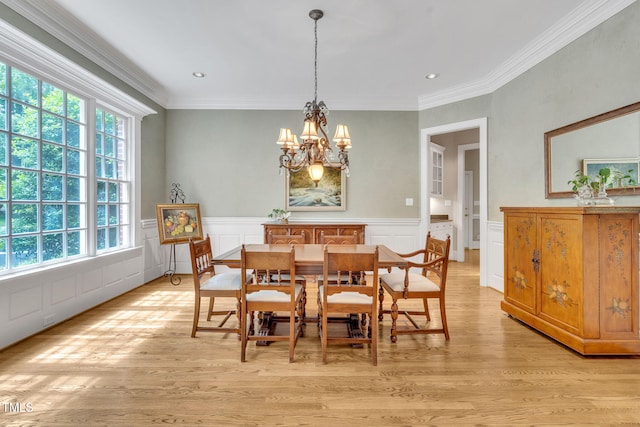 dining room with a chandelier, light wood-style flooring, ornamental molding, a decorative wall, and wainscoting
