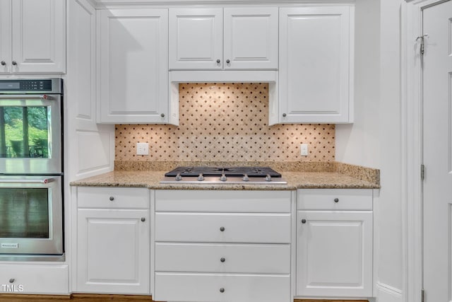 kitchen featuring stainless steel appliances, white cabinetry, and tasteful backsplash