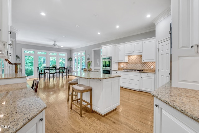 kitchen featuring stainless steel appliances, crown molding, a ceiling fan, white cabinetry, and tasteful backsplash