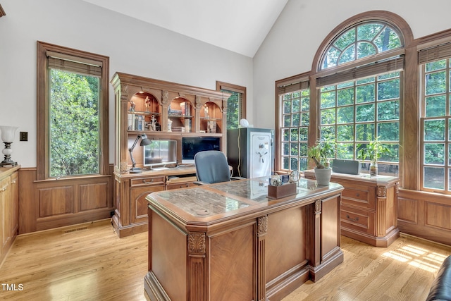office space with light wood-style floors, vaulted ceiling, and wainscoting