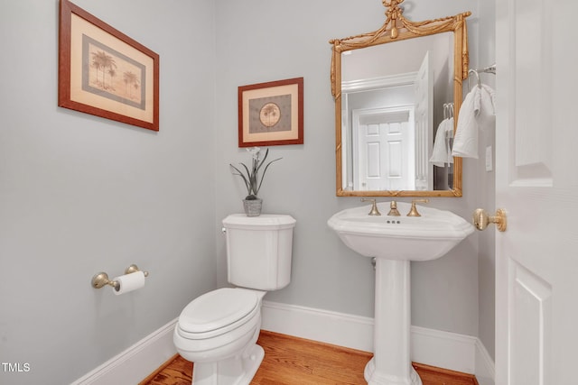 bathroom with toilet, wood finished floors, and baseboards