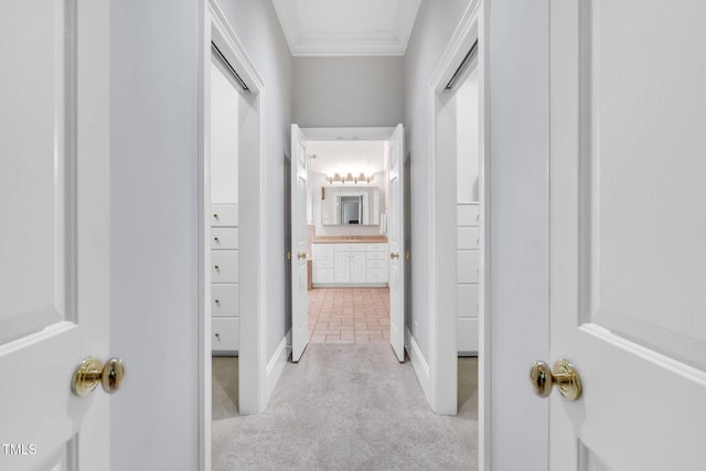 corridor with ornamental molding, baseboards, and carpet floors