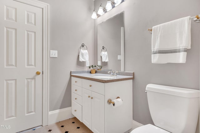 bathroom with toilet, vanity, and baseboards