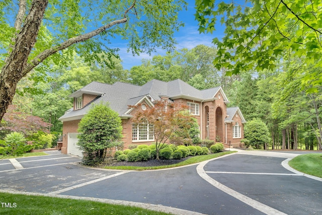 view of front of property featuring brick siding, a garage, asphalt driveway, and a shingled roof