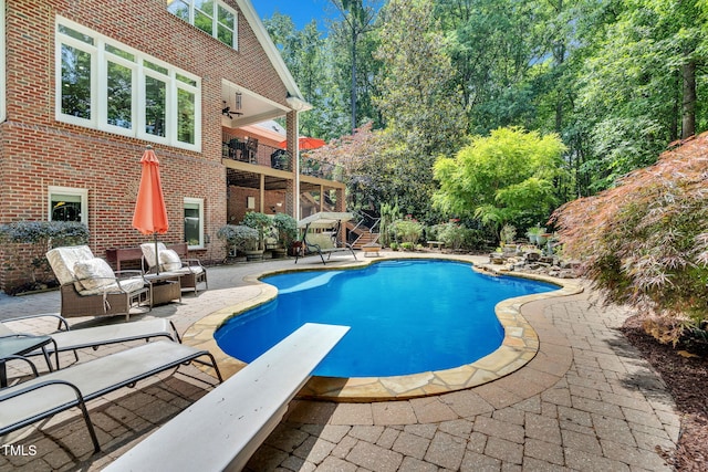 outdoor pool featuring a patio, a diving board, and an outdoor living space