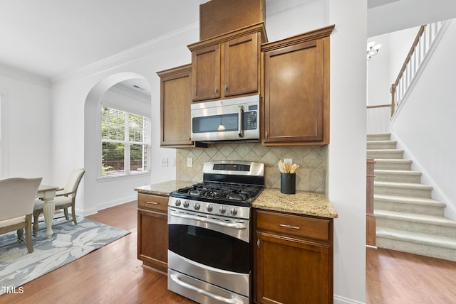 1720 Laurel Park Pl, Cary, NC 27511 - kitchen with stainless steel appliances, dark wood-type flooring, backsplash, light stone countertops, and arched walkways