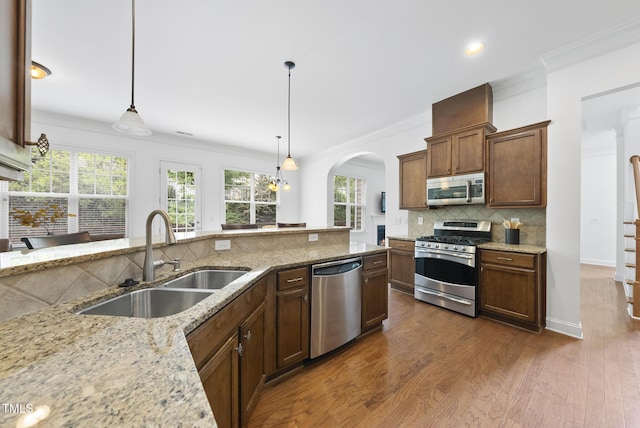 1720 Laurel Park Pl, Cary, NC 27511 - kitchen featuring appliances with stainless steel finishes, a sink, arched walkways, ornamental molding, and light stone counters