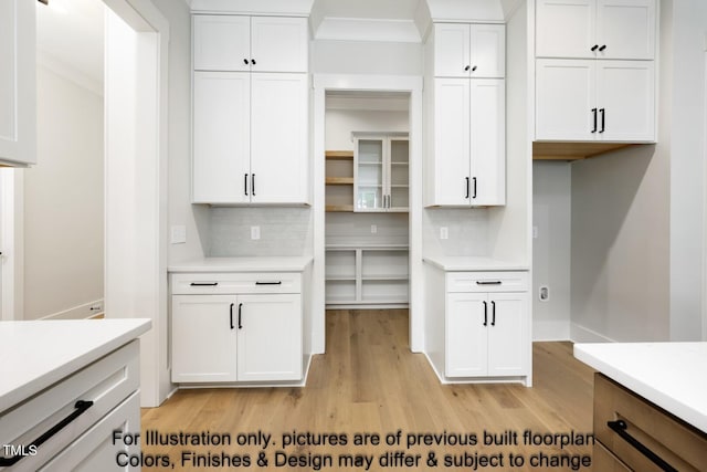 kitchen with light countertops, light wood-style floors, backsplash, and white cabinets