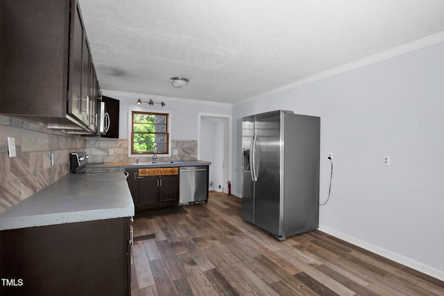 5830 Mcdougal Dr, Fayetteville, NC 28304 - kitchen featuring appliances with stainless steel finishes, dark brown cabinets, ornamental molding, backsplash, and dark wood-style floors