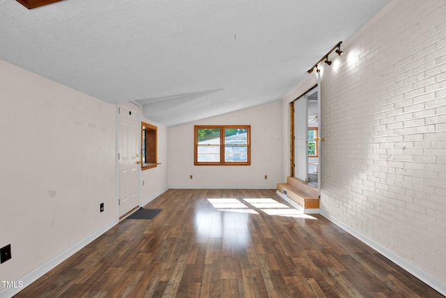 5830 Mcdougal Dr, Fayetteville, NC 28304 - spare room with vaulted ceiling, brick wall, dark wood-style floors, and baseboards