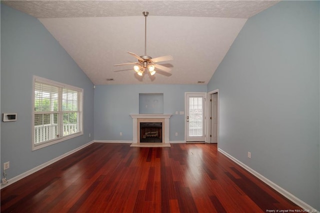 unfurnished living room featuring a ceiling fan, wood finished floors, a fireplace with flush hearth, healthy amount of natural light, and high vaulted ceiling