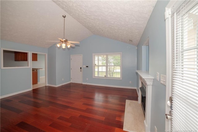 unfurnished living room with a ceiling fan, a textured ceiling, wood finished floors, a fireplace with flush hearth, and lofted ceiling
