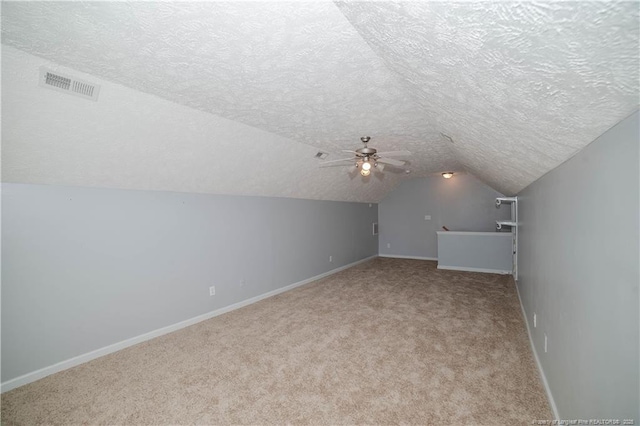 bonus room featuring a textured ceiling, carpet floors, vaulted ceiling, baseboards, and ceiling fan