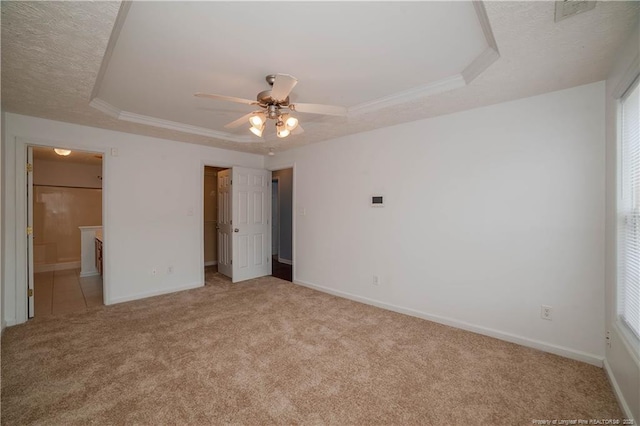 unfurnished bedroom with carpet flooring, a tray ceiling, baseboards, a textured ceiling, and ensuite bathroom