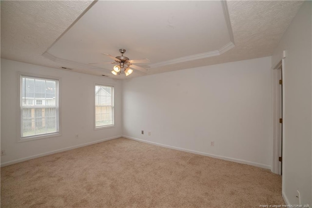 carpeted empty room featuring a tray ceiling, a textured ceiling, ceiling fan, and baseboards
