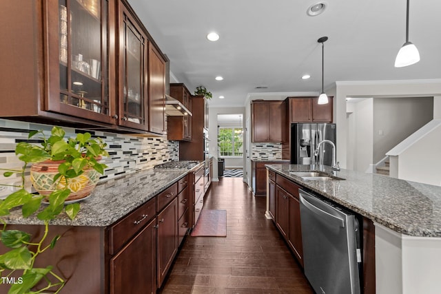 kitchen featuring appliances with stainless steel finishes, a sink, crown molding, dark stone counters, and decorative backsplash