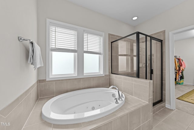 full bath featuring a shower stall, a tub with jets, and tile patterned floors