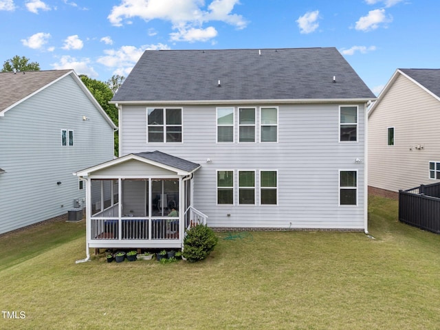 rear view of house with cooling unit, a lawn, a sunroom, and roof with shingles