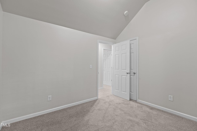 carpeted spare room with lofted ceiling and baseboards