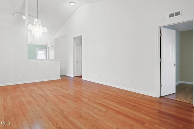 3108 Forrestal Dr, Durham, NC 27703 - empty room featuring a chandelier, light wood-style floors, high vaulted ceiling, and baseboards