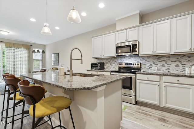 127 Manordale Dr, Chapel Hill, NC 27517 - kitchen with stainless steel appliances, backsplash, a sink, a kitchen breakfast bar, and light wood-style flooring