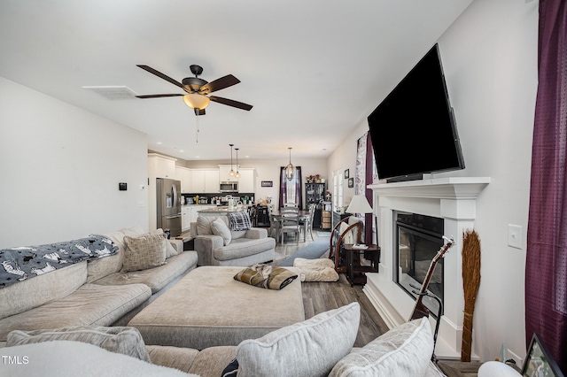 living room with wood finished floors, ceiling fan, a glass covered fireplace, baseboards, and recessed lighting