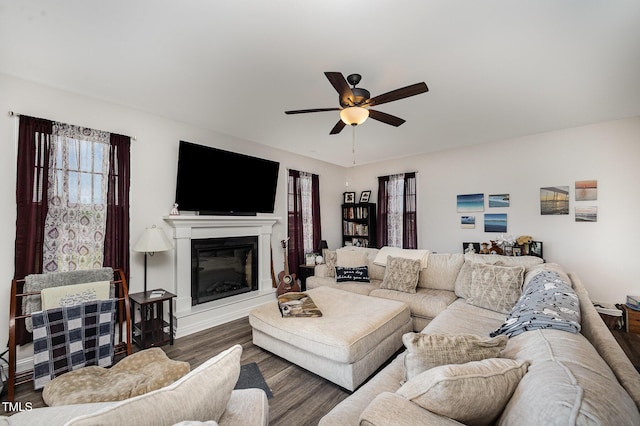 living area featuring ceiling fan, wood finished floors, and a glass covered fireplace