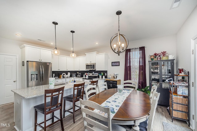 dining room featuring a chandelier, light wood-style flooring, and recessed lighting