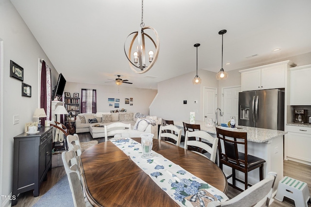 dining space with wood finished floors, a chandelier, and ceiling fan