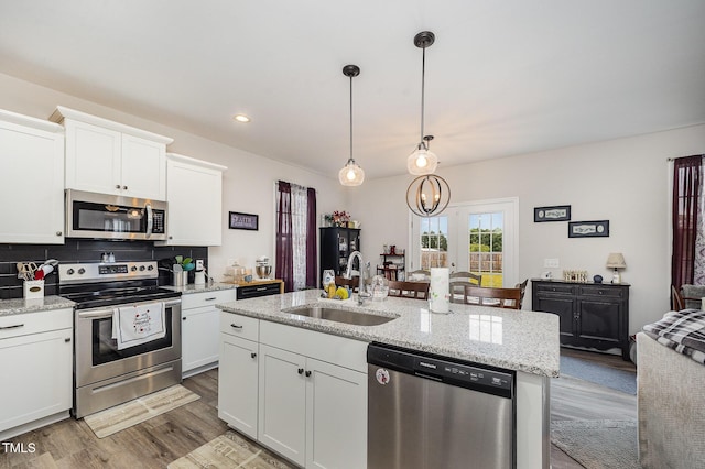 kitchen featuring stainless steel appliances, a sink, wood finished floors, white cabinetry, and a kitchen island with sink