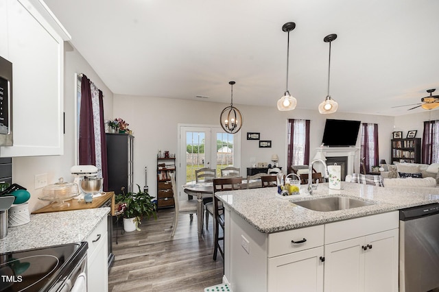 kitchen featuring a sink, stainless steel appliances, light wood finished floors, open floor plan, and pendant lighting