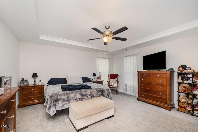 bedroom with a tray ceiling, ornamental molding, light colored carpet, and ceiling fan