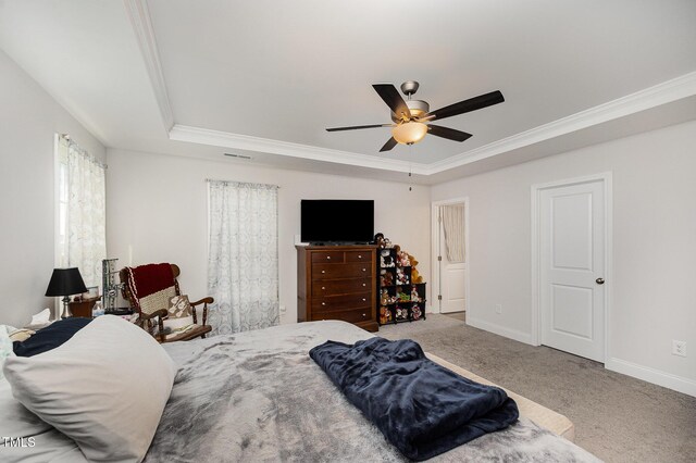 carpeted bedroom with a tray ceiling, crown molding, baseboards, and ceiling fan