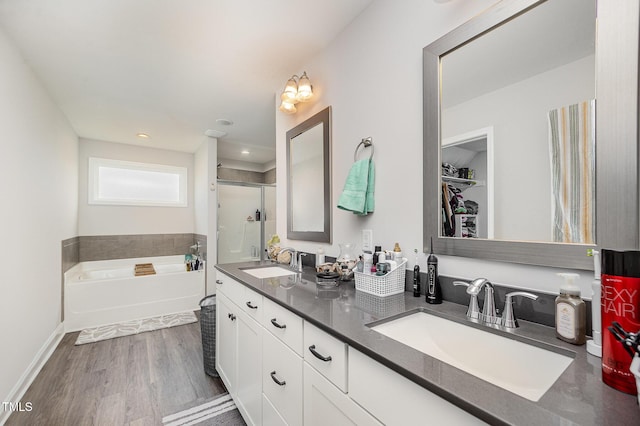 full bath with a shower stall, a garden tub, double vanity, wood finished floors, and recessed lighting