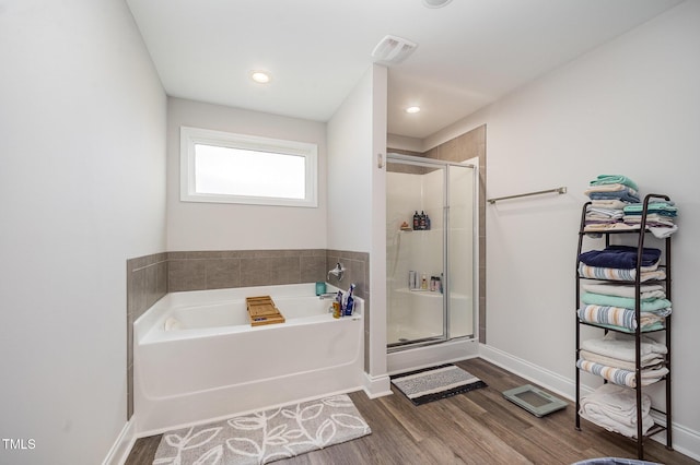 bathroom featuring a stall shower, a garden tub, wood finished floors, and baseboards