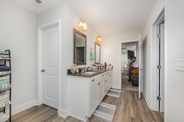 bathroom with wood finished floors, double vanity, and baseboards
