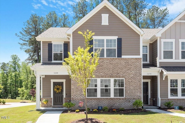 1440 Latham Garden Dr, Wake Forest, NC 27587 - view of front of home featuring brick siding, a front lawn, board and batten siding, and a shingled roof