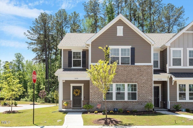 1440 Latham Garden Dr, Wake Forest, NC 27587 - view of front of house featuring a front lawn, brick siding, roof with shingles, and board and batten siding