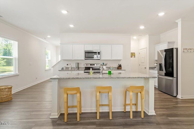 1440 Latham Garden Dr, Wake Forest, NC 27587 - kitchen featuring stainless steel appliances, crown molding, a center island with sink, white cabinets, and a breakfast bar area